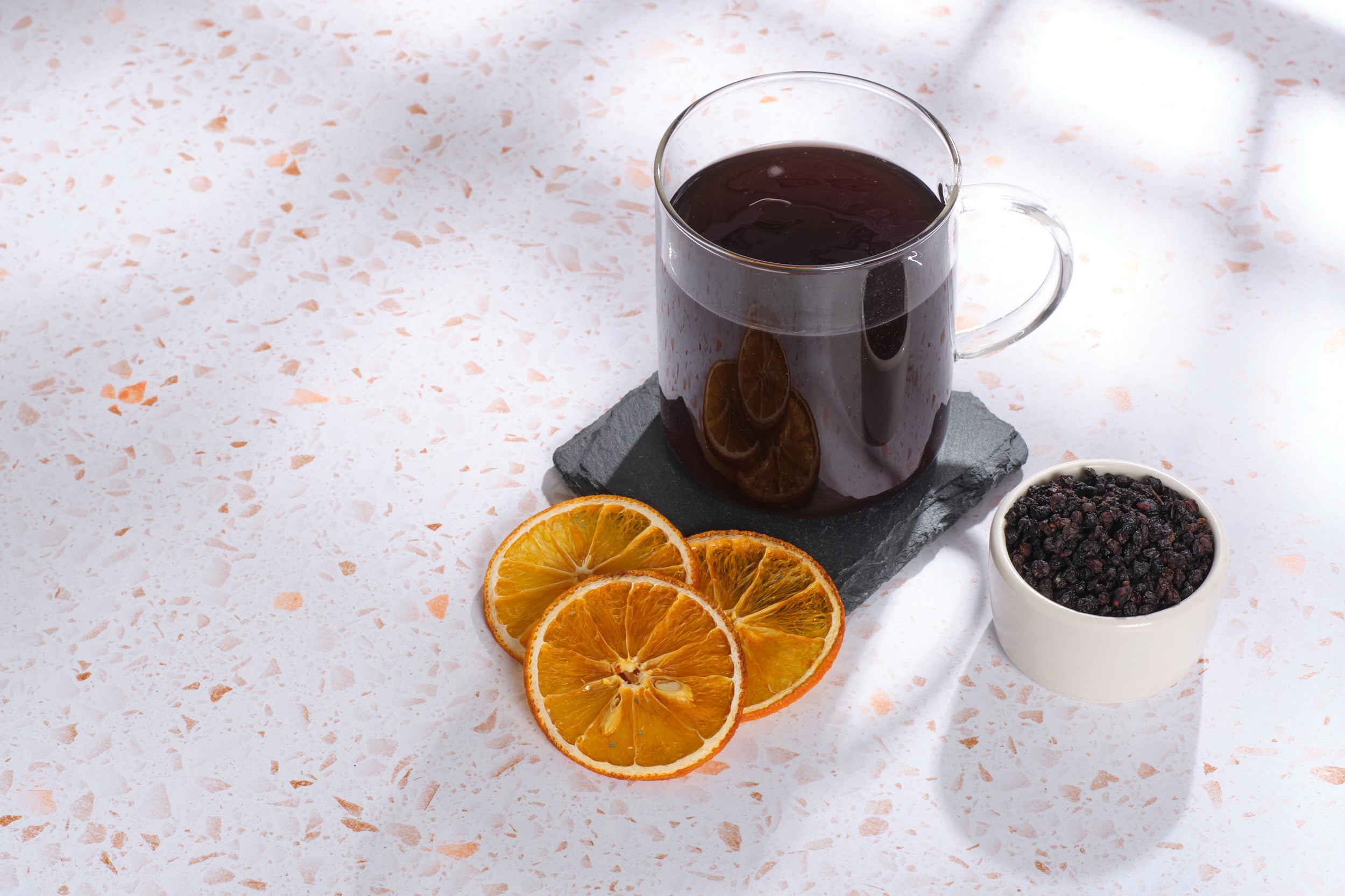 The ingredients of Atomic Fungi Functional Mushroom Booster Shot's tea around a cup of the tea, against a white tabletop.