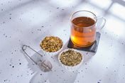 The ingredients of Atomic Fungi Functional Mushroom Chill Tonic's tea around a cup of the tea, against a white tabletop.